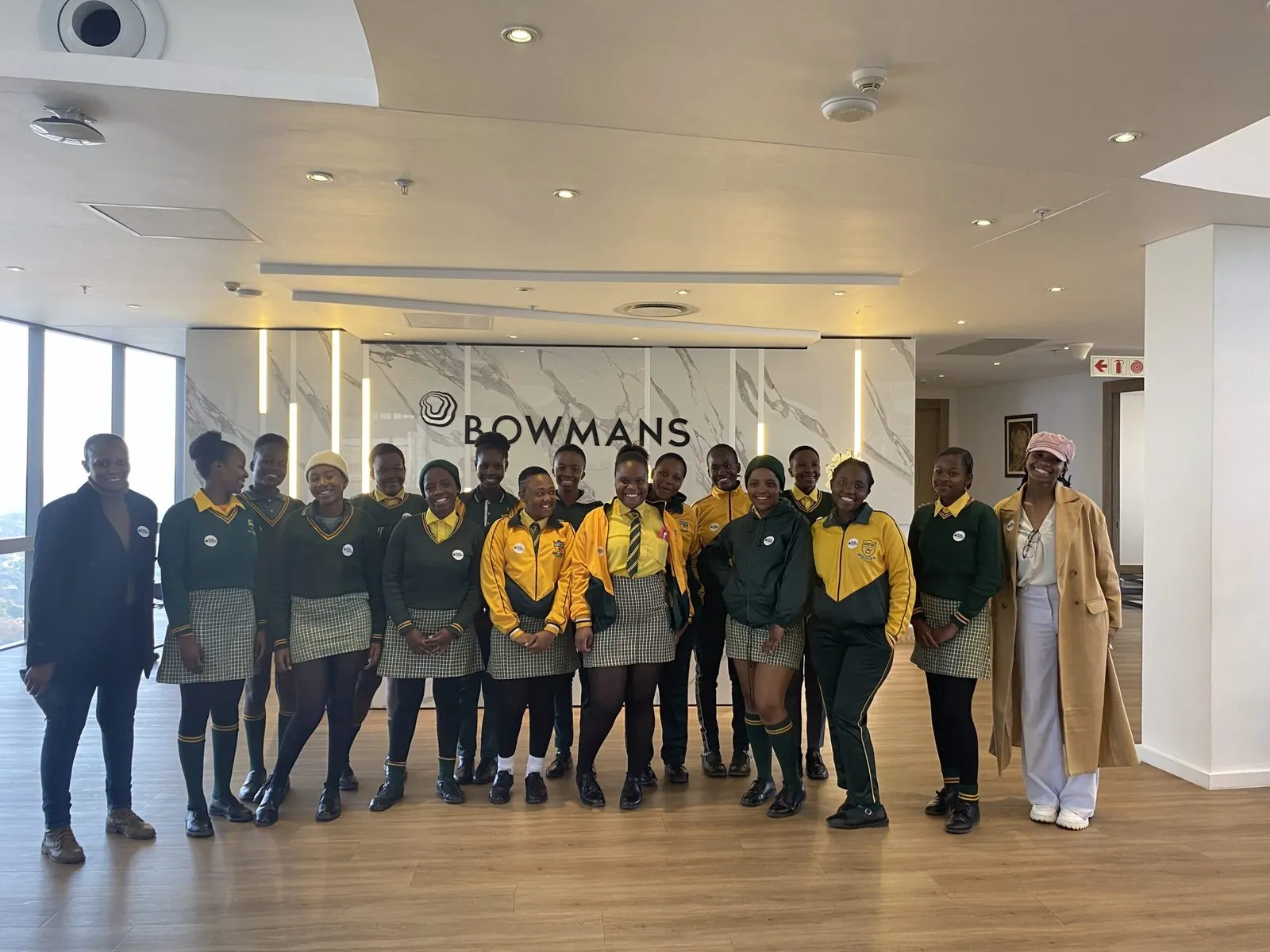 Girls in school uniform standing together with their hosts in a corporate office reception